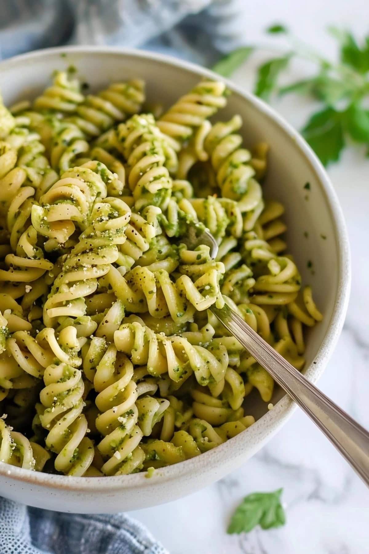 Super Close Up of Green Pesto Pasta in a Bowl with a Fork