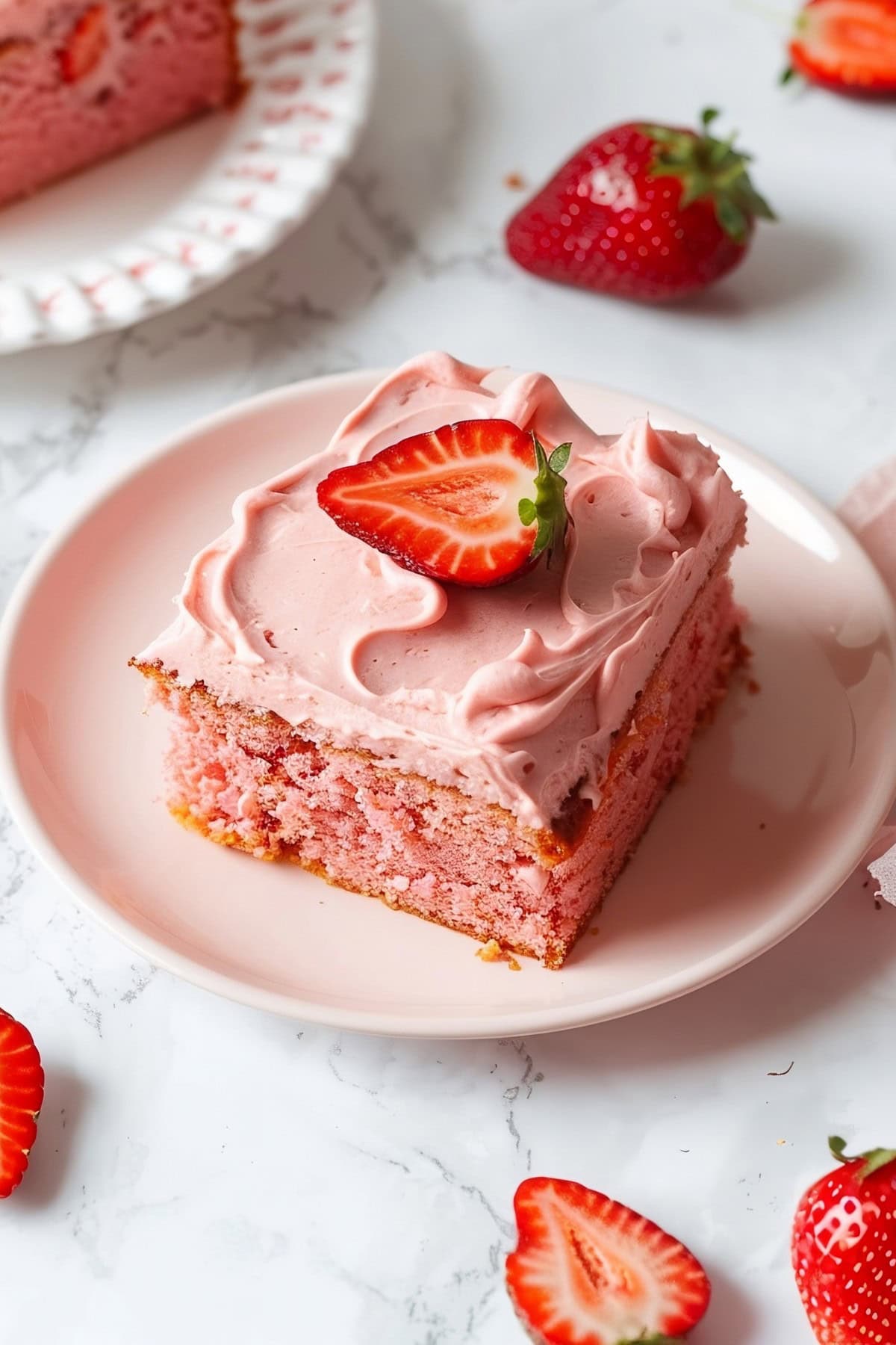 A slice of strawberry sheet cake with frosting in a plate.