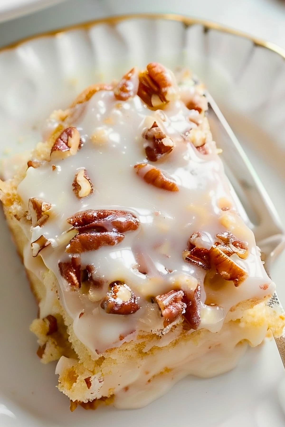 Close Up of a Slice of White Texas Sheet Cake with White Frosting and Pecans on a White Plate