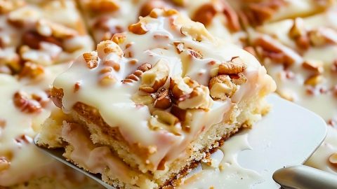 Slice of White Texas Sheet Cake with Pecans on a Spatula