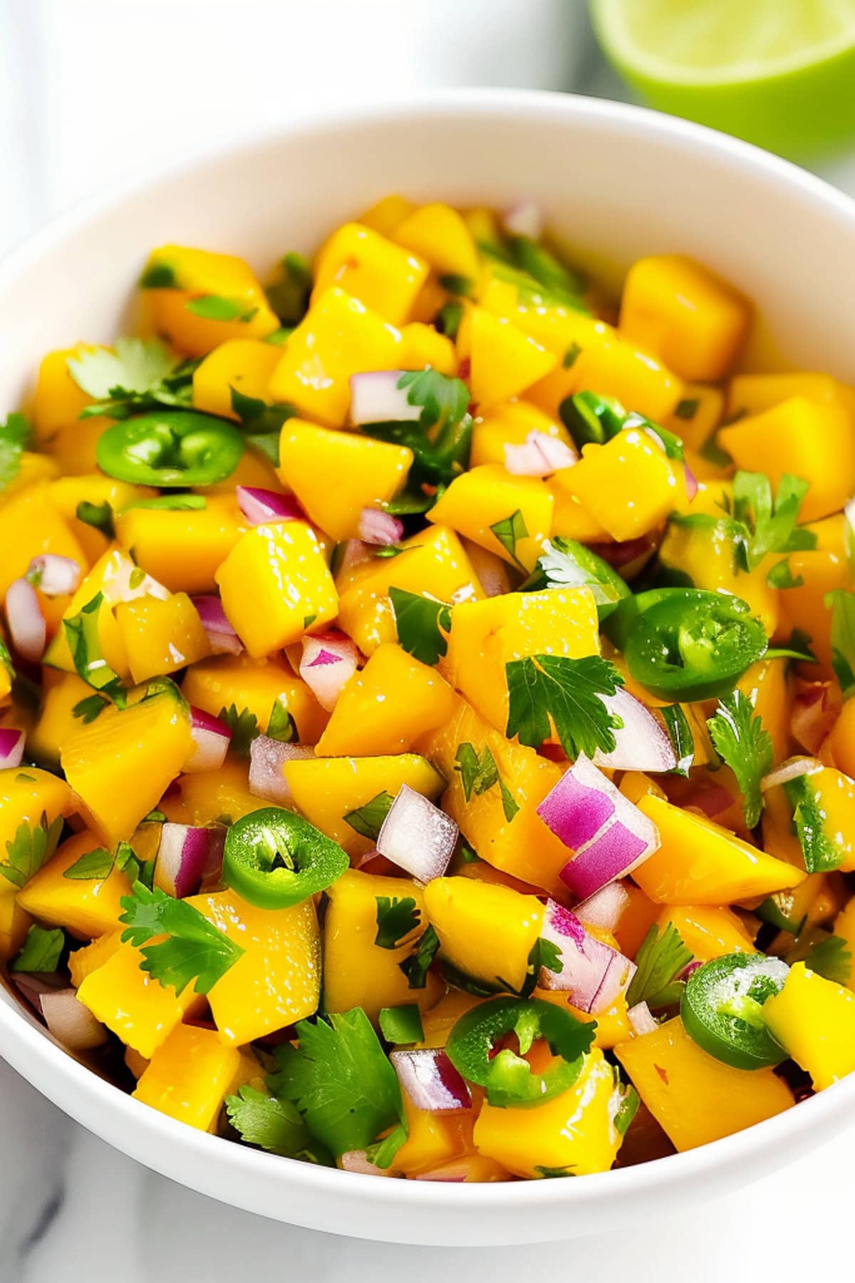 White bowl filled with fresh mango, jalapeño, and red onion salsa, close up