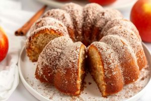 Whole cinnamon sugar coated apple cider donut bundt cake in a white plate.