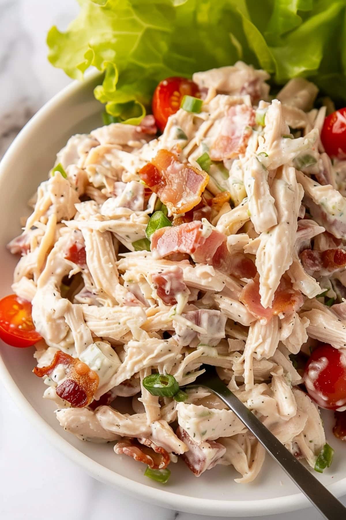 Freshly made BLT chicken salad in a bowl, garnished with chives.