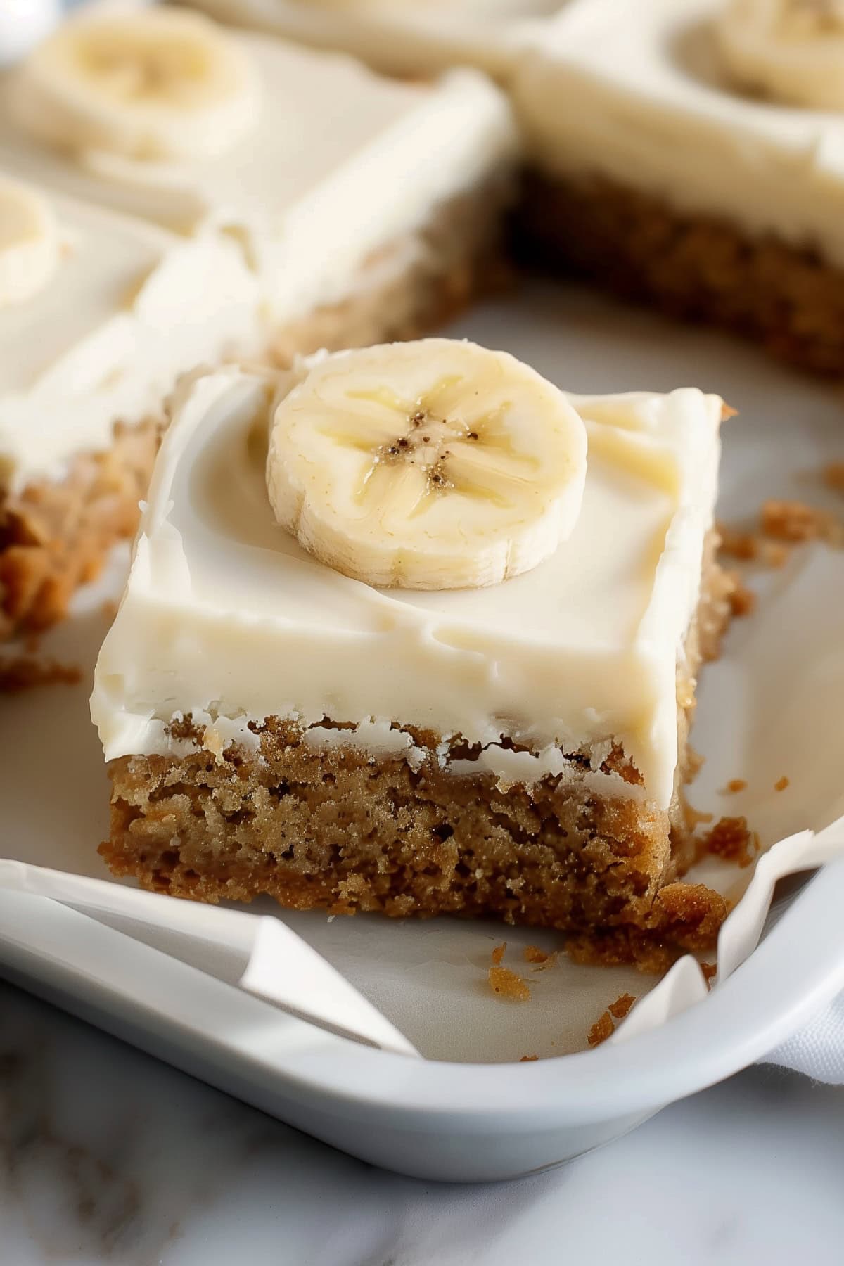 Homemade banana cake with cream cheese frosting and a slice of fresh banana.