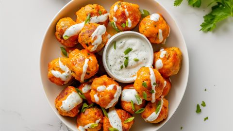 Buffalo chicken meatballs drizzled with hot sauce, cilantro and chopped chives.