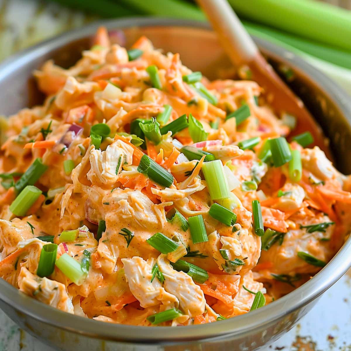 Buffalo chicken salad mixed in a large metal mixing bowl.