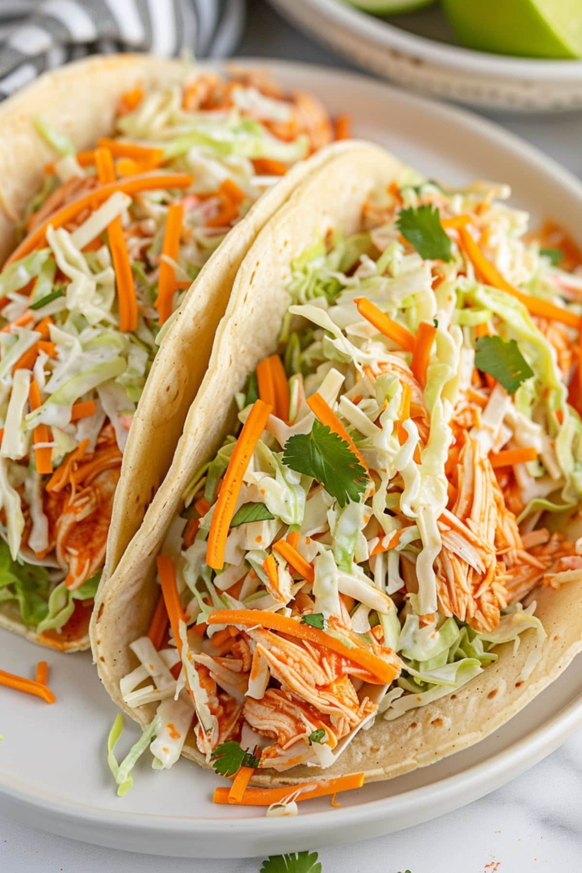 tacos with shredded buffalo chicken and shredded lettuce and carrots toppings.