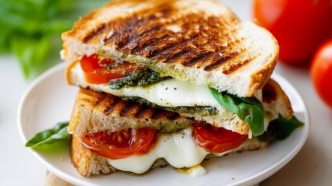 Sliced in half grilled cheese sandwich served on a white plate.