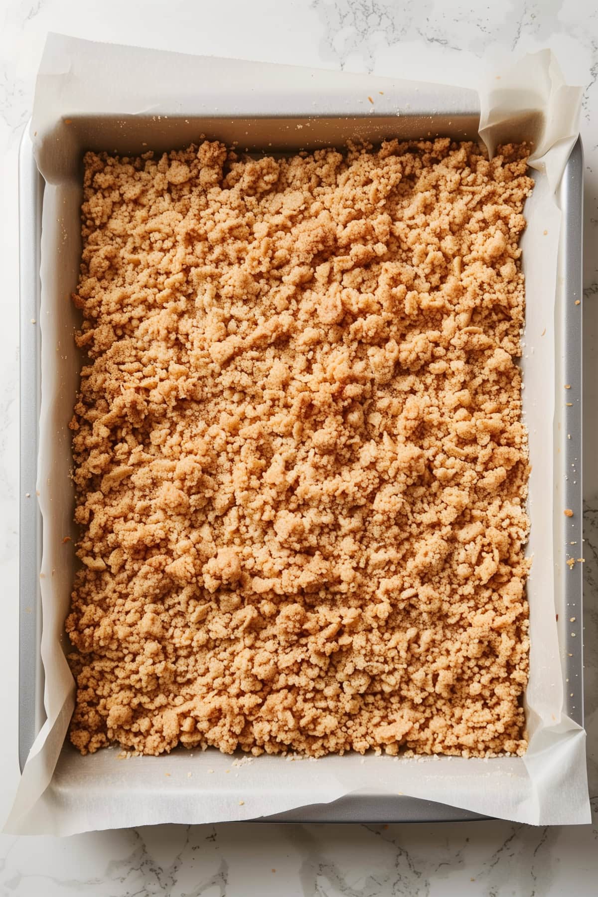 A baking pan filled with caramel apple cheesecake bars topped with brown sugar streusel.