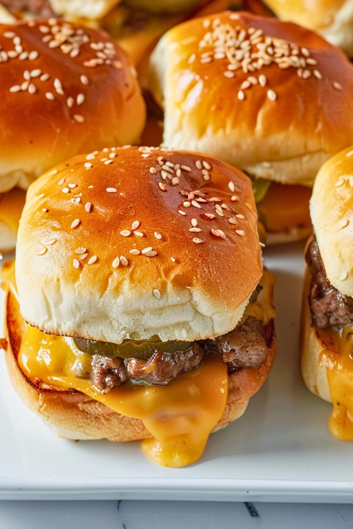 Cheeseburger sliders with melted cheese, beef patty and sliced pickles.