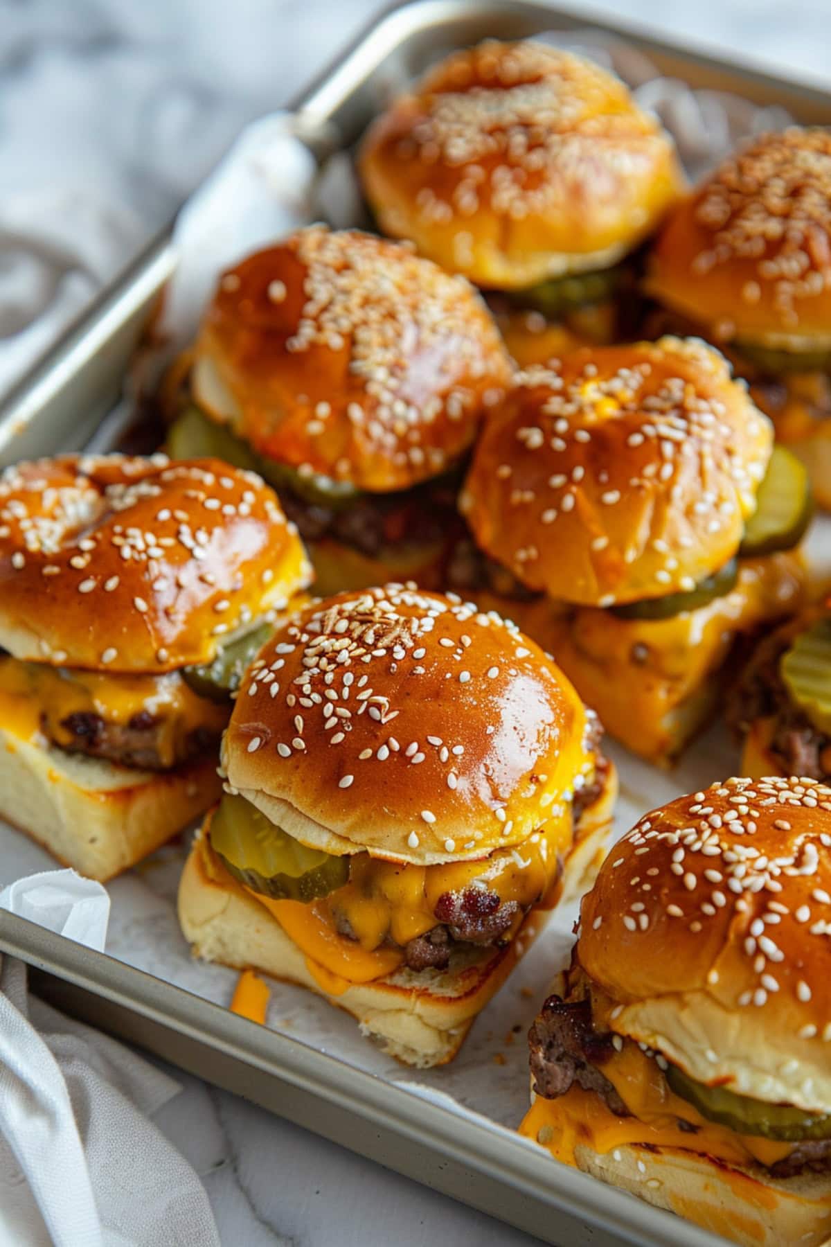 Cheeseburger sliders in a baking pan top view on a white marble table.