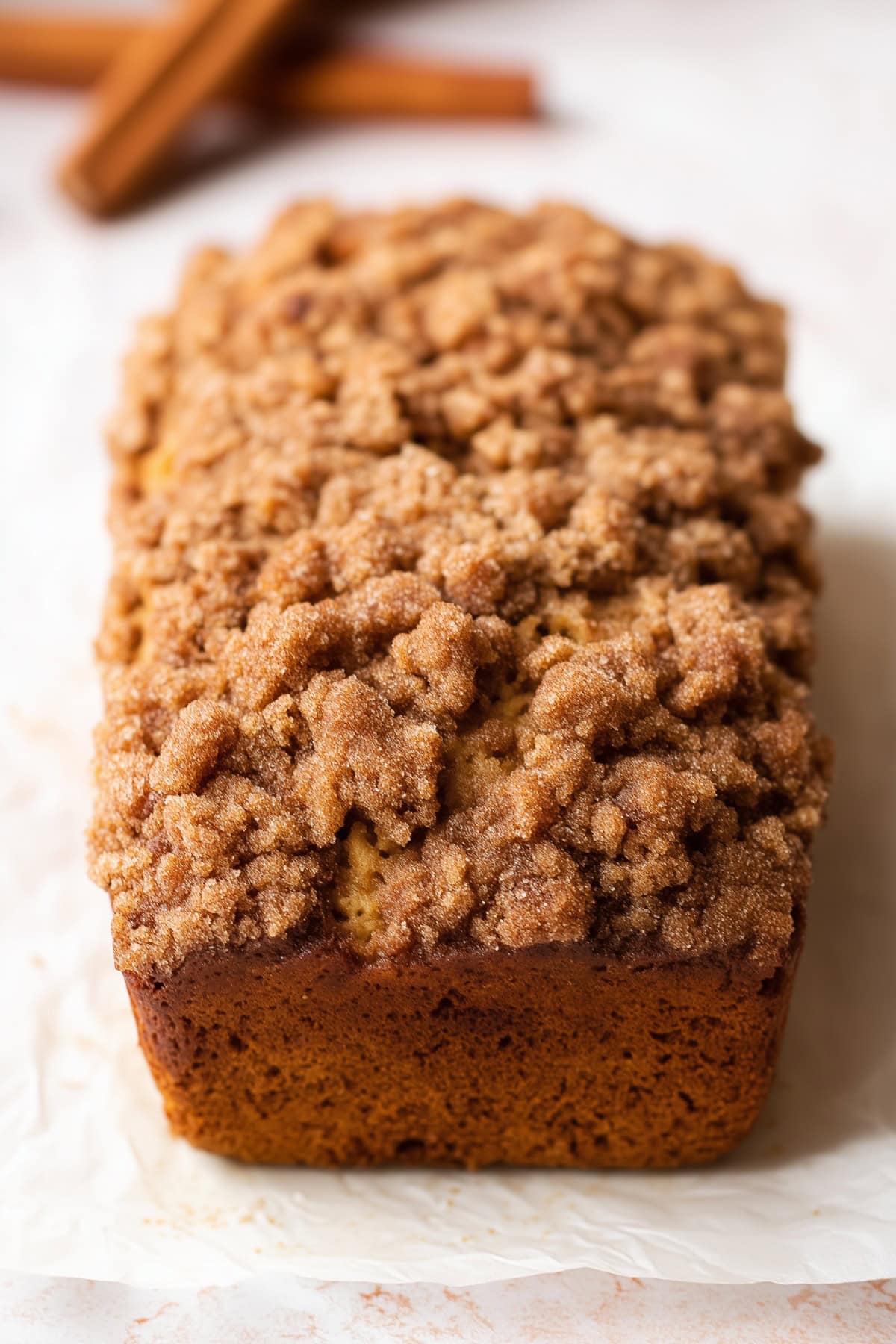 A whole loaf of cinnamon crunch banana bread on a white parchment paper.