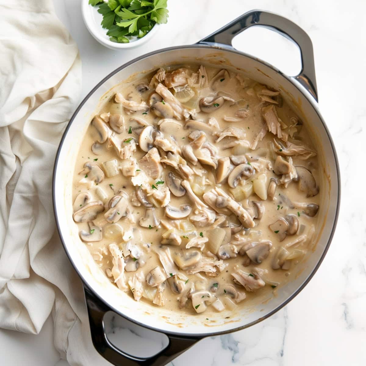 Overhead view of turkey tetrazzini with creamy sauce and mushrooms in a dutch oven, top down view