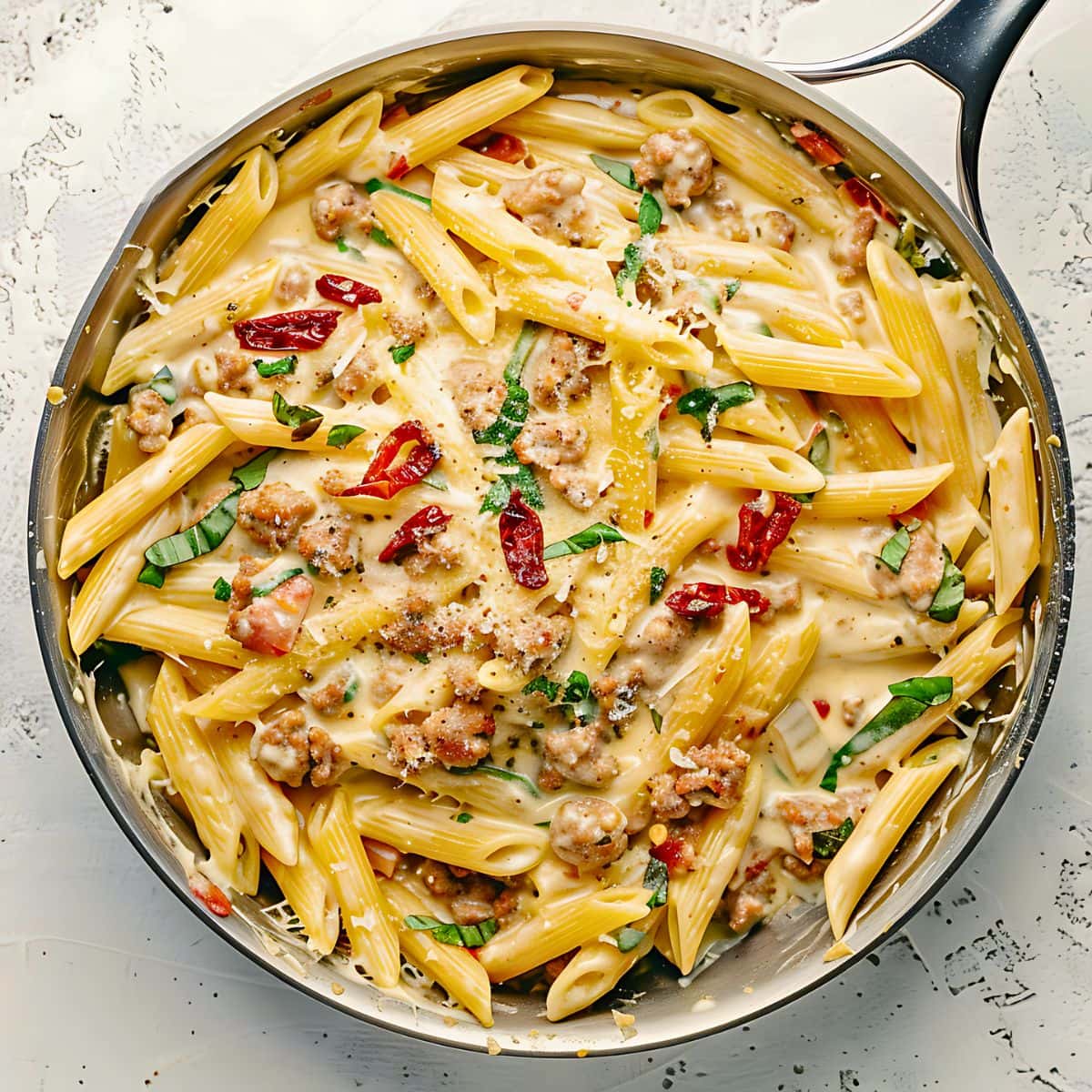 Creamy and cheesy Tuscan sausage in a stainless pan, top down view