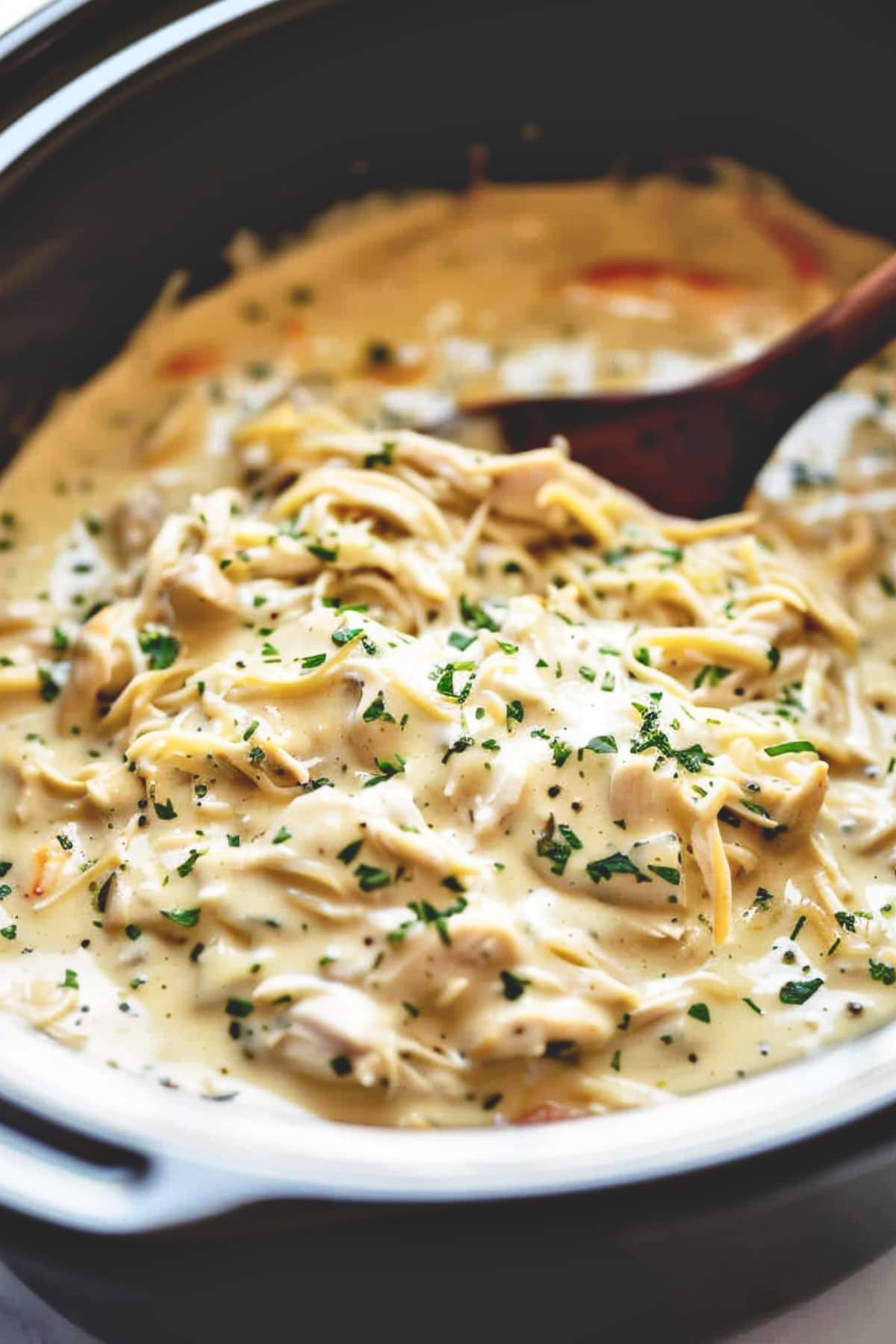 Shredded chicken in creamy and cheesy sauce in a slow cooker.