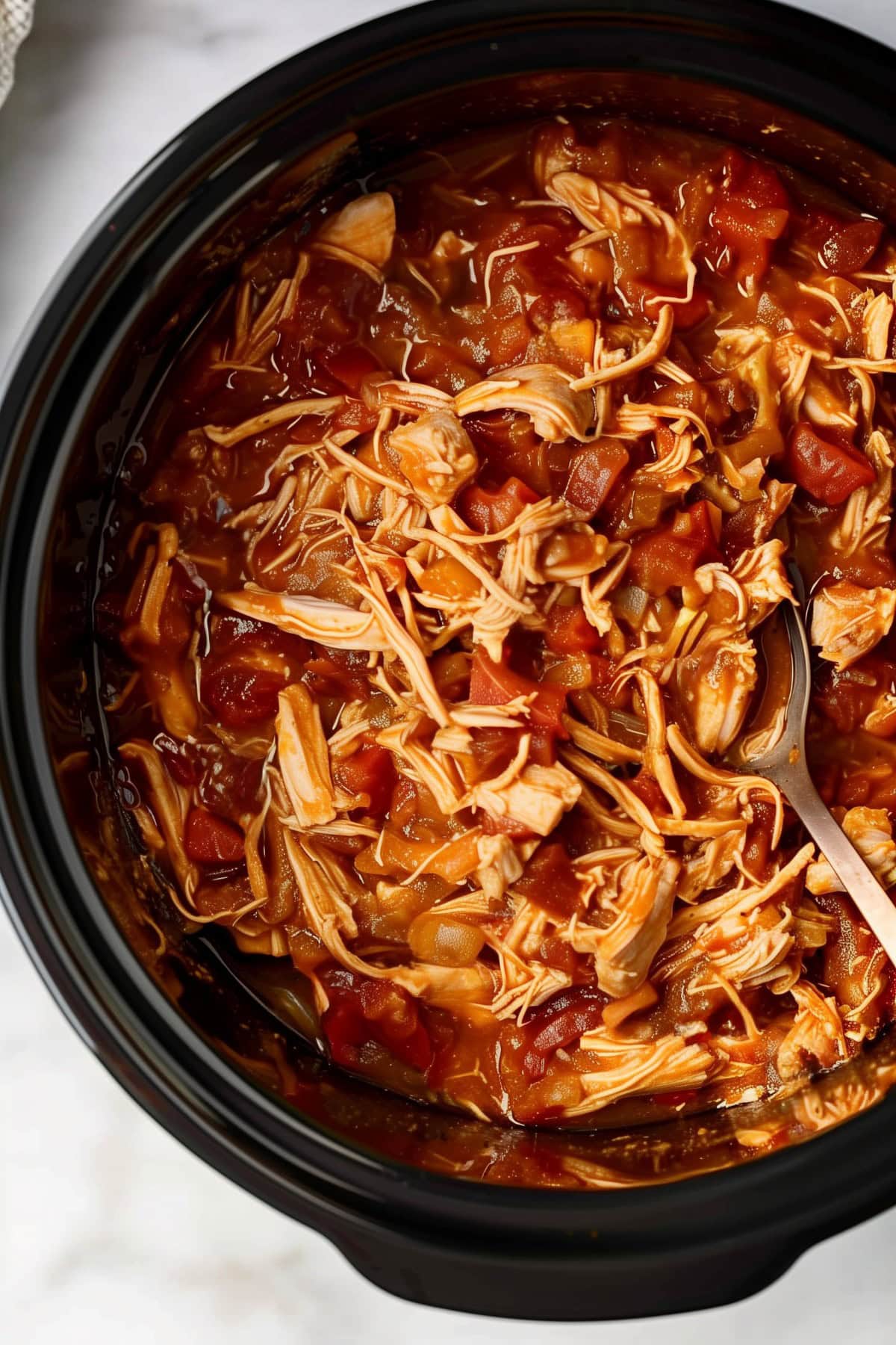 Close-up of shredded salsa chicken in a slow cooker.