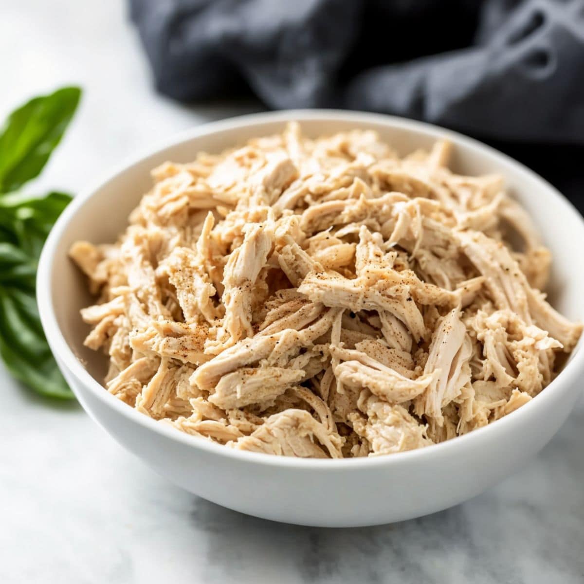 Shredded chicken served in a white bowl.