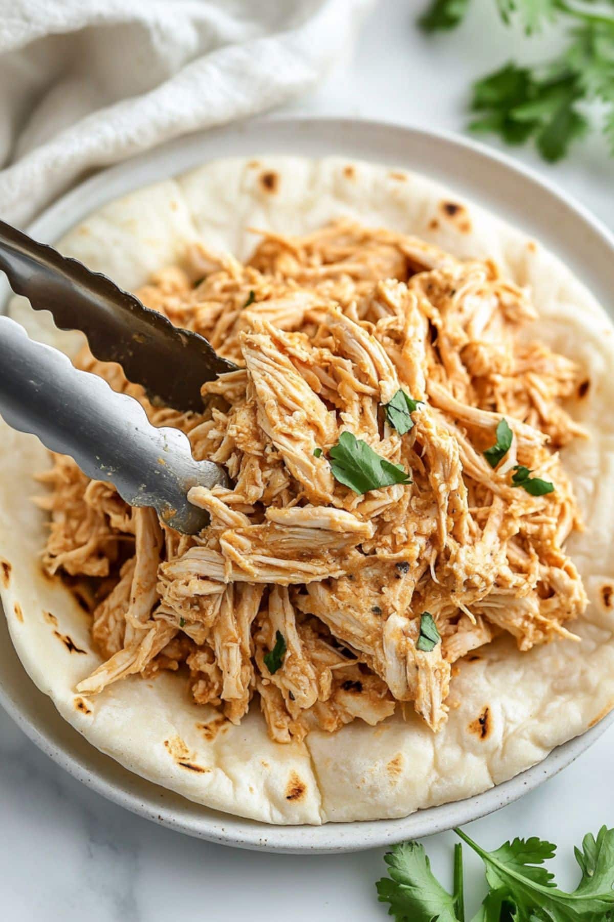 Shredded chicken placed on top of pita bread. 