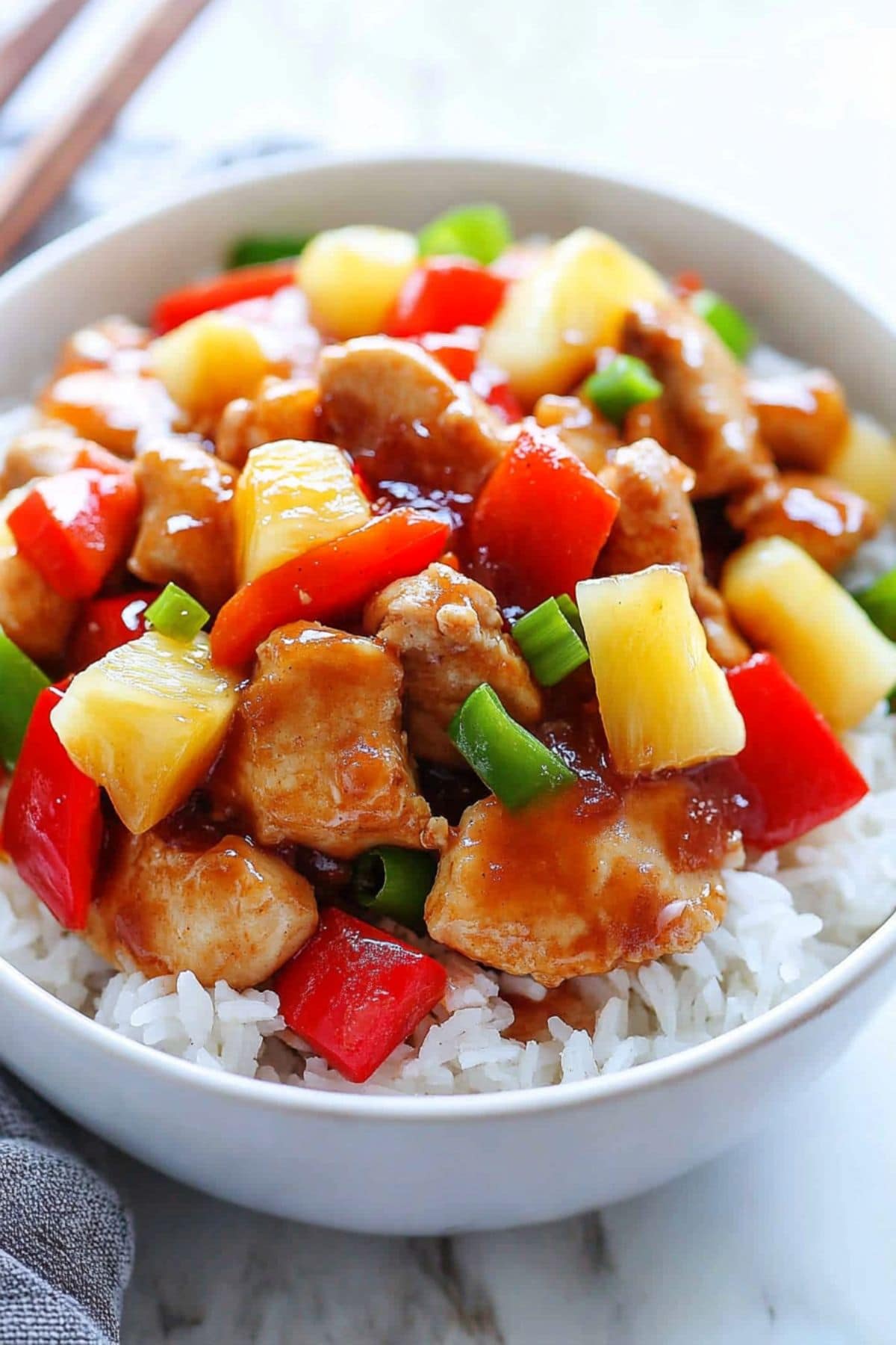 Sweet and sour chicken served with white rice on a white bowl.