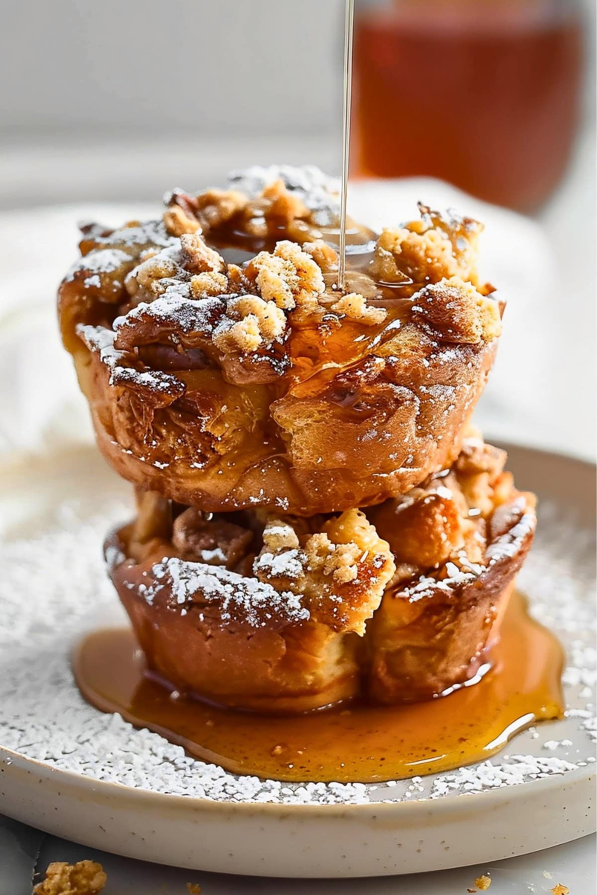 Freshly baked French toast muffins topped with a dusting of powdered sugar and maple syrup drizzle.