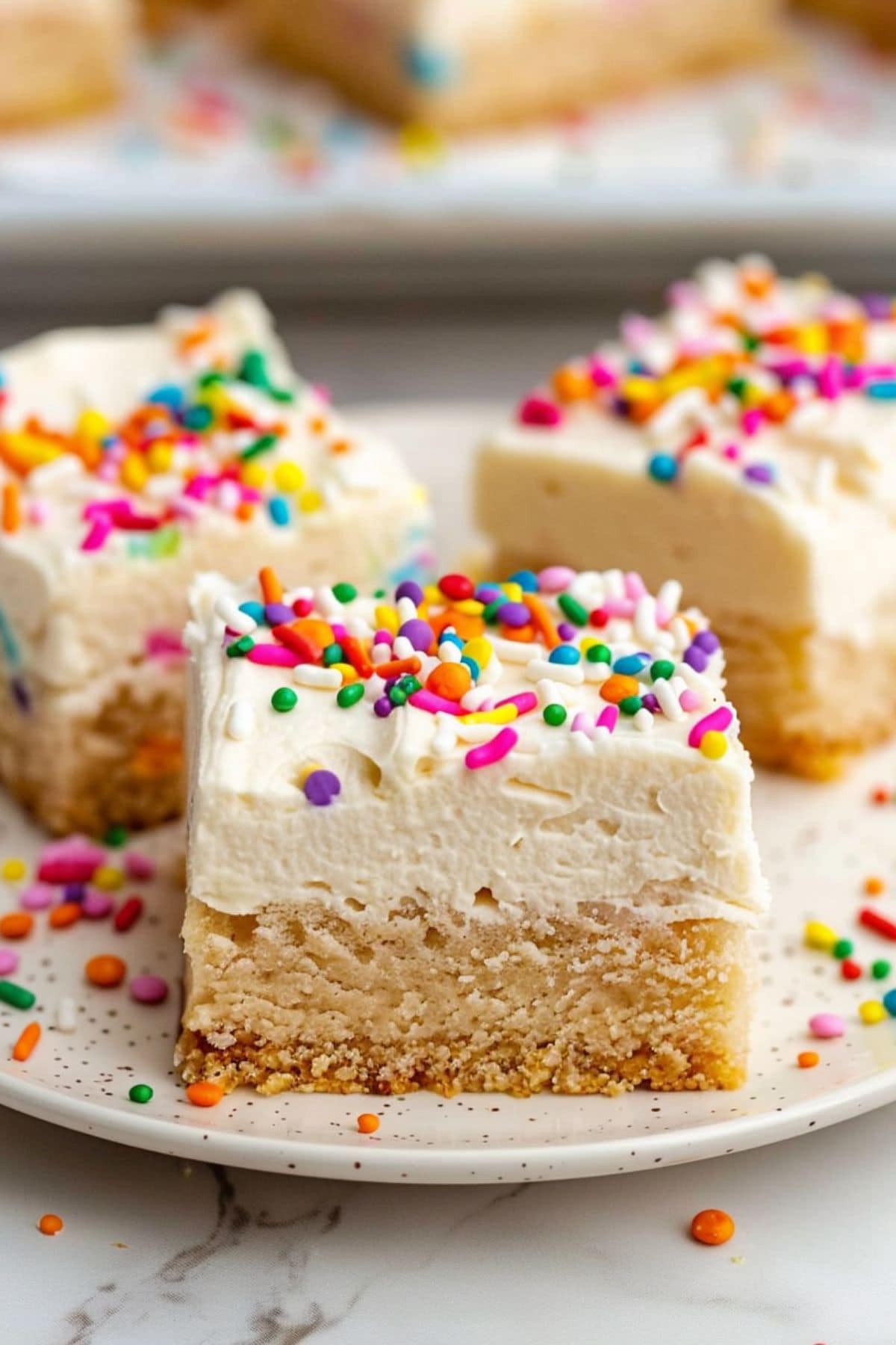 Slices of frosted sugar cookie bars served on a white plate.