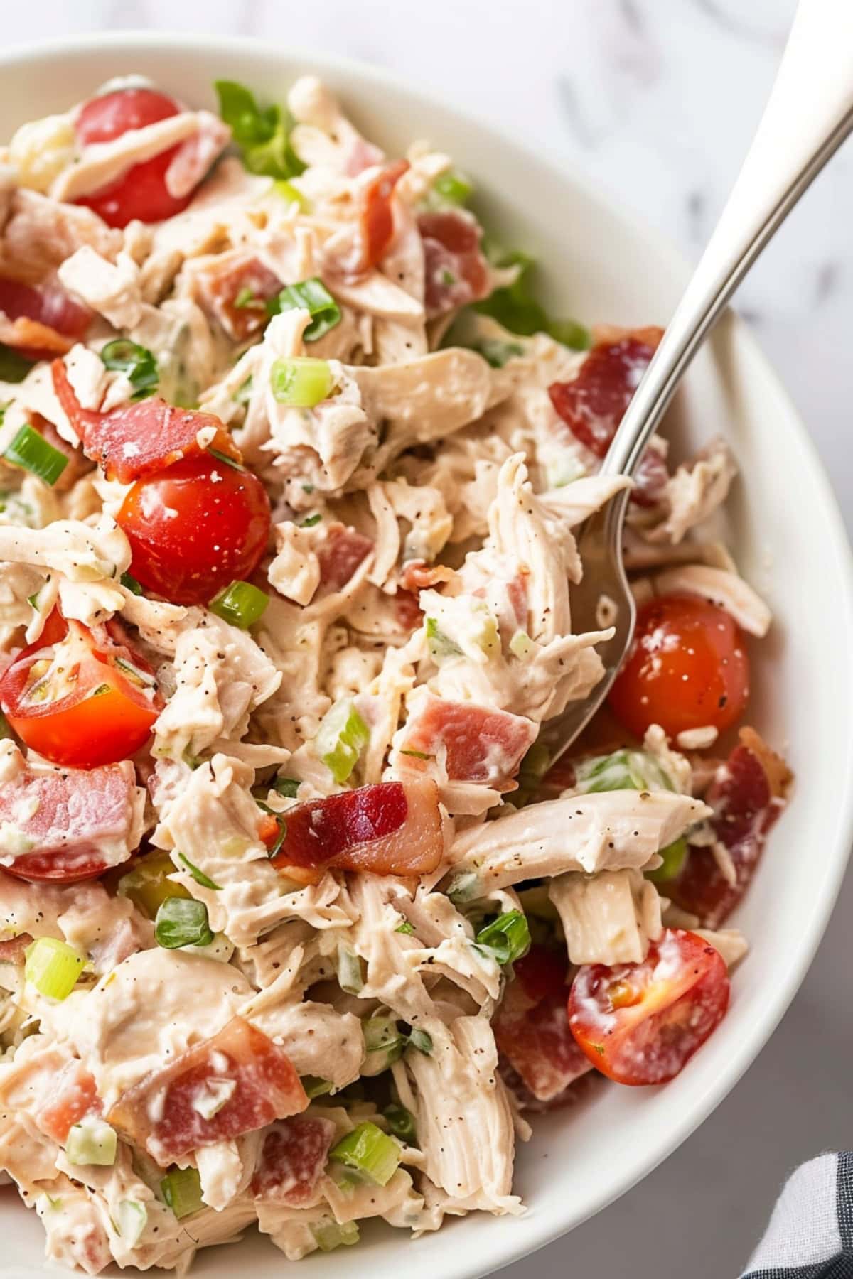 A colorful BLT chicken salad with crispy bacon, juicy tomatoes, shredded chicken, and fresh lettuce.