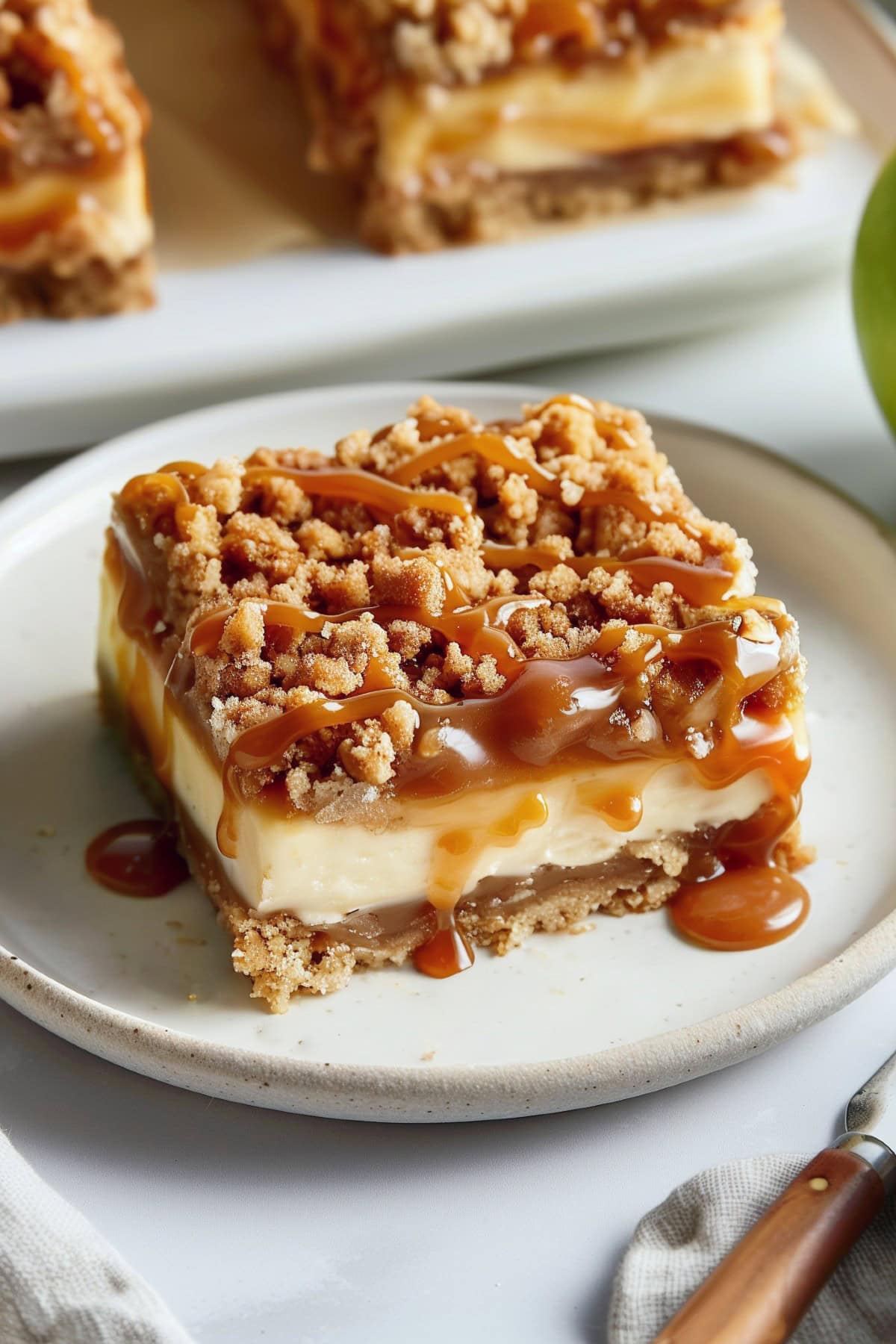 Freshly baked caramel apple cheesecake bars with a golden streusel topping and caramel sauce.