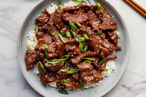 Classic Mongolian Beef Topped with Green Onions and Sesame Seeds, Served with Rice.