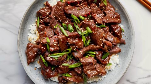 Classic Mongolian Beef Topped with Green Onions and Sesame Seeds, Served with Rice.