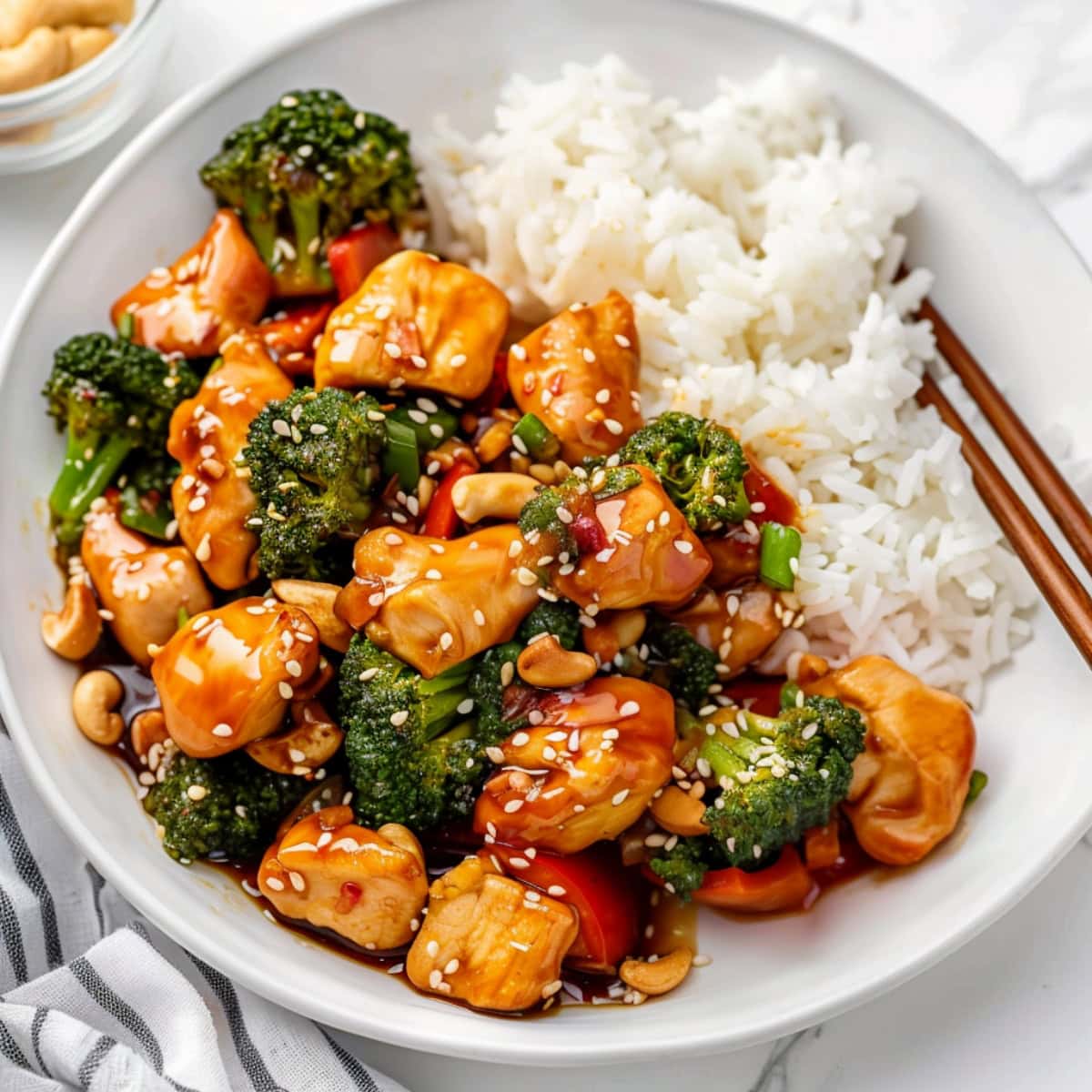 Stir-fry chicken with teriyaki sauce served with rice, featuring chopsticks in a white plate.