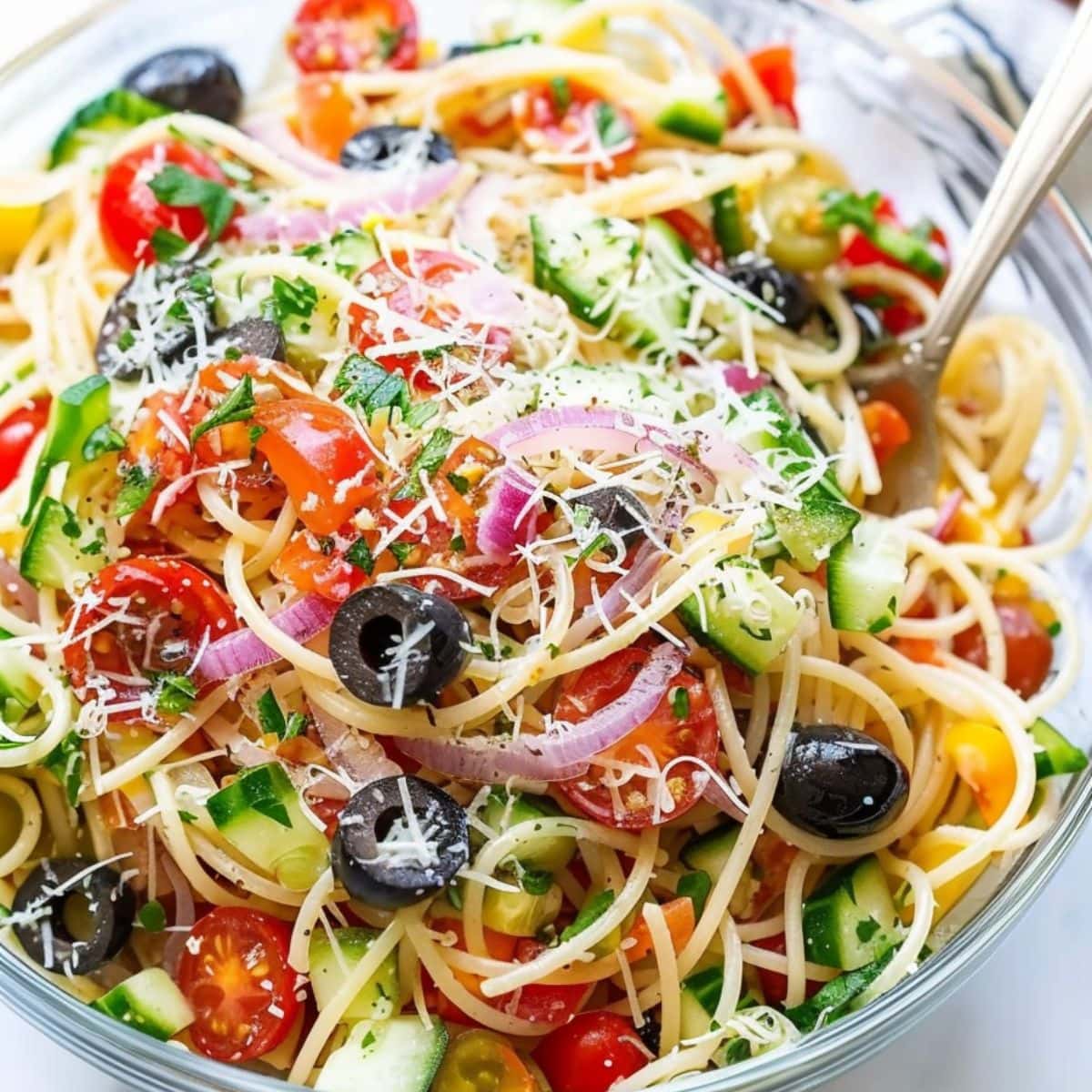 Italian spaghetti pasta tossed in a large glass salad bowl. 