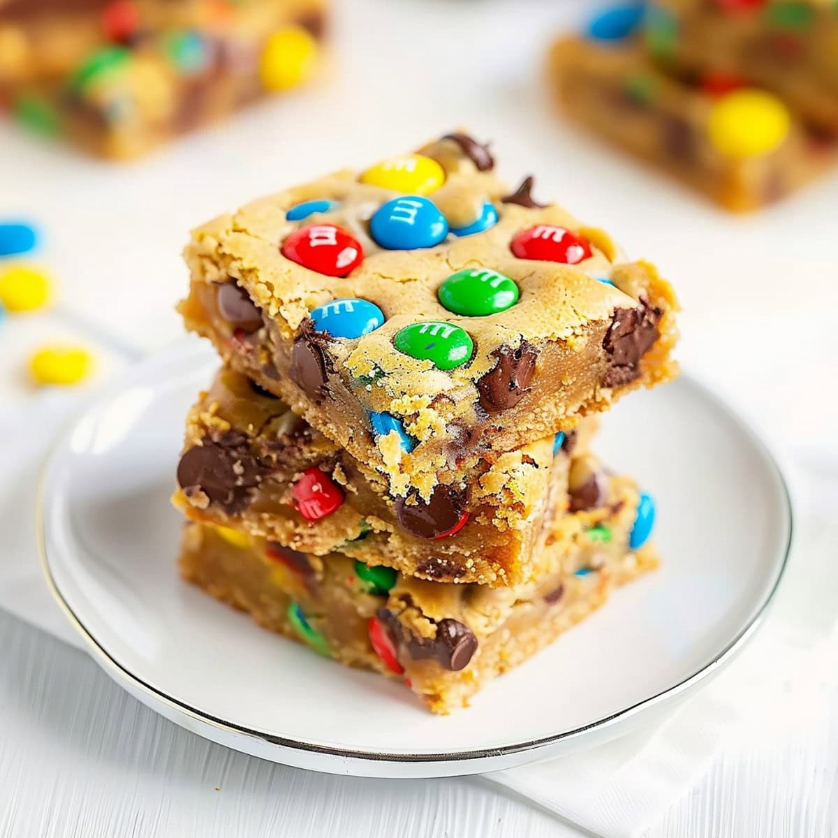 Stack M&M Cookie Bars with Chocolate Chips in a Plate.