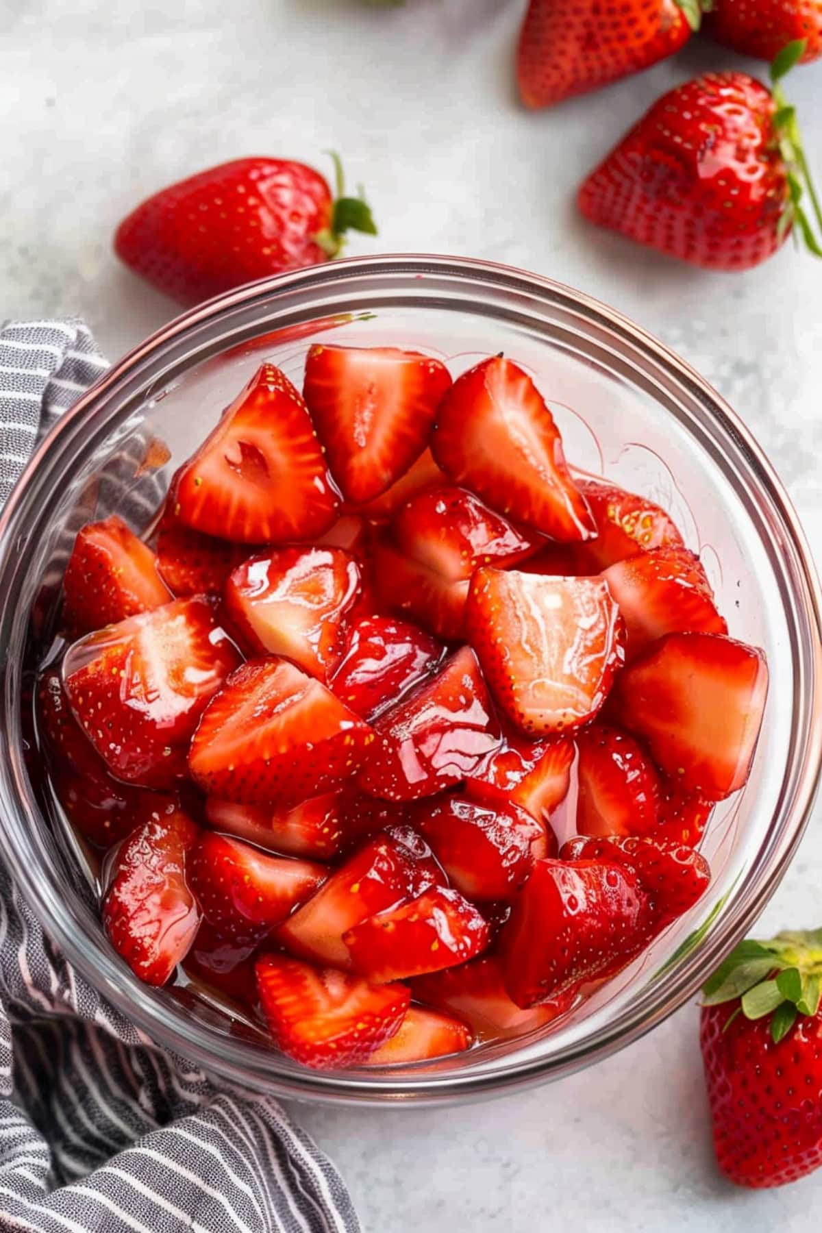 A glass bowl filled with macerated strawberries, top view.