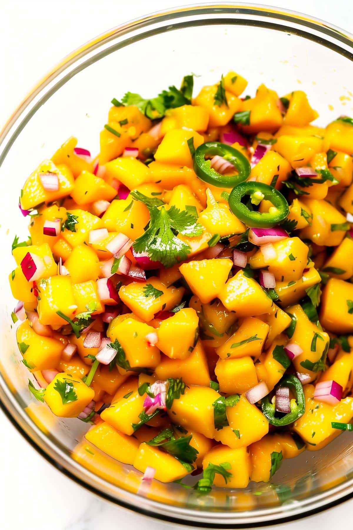 Irresistible mango salsa served in a glass bowl with a garnish of fresh cilantro, top view