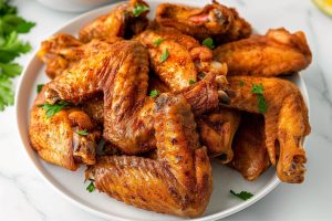 Old bay seasoning coated baked chicken wings served on a white plate.