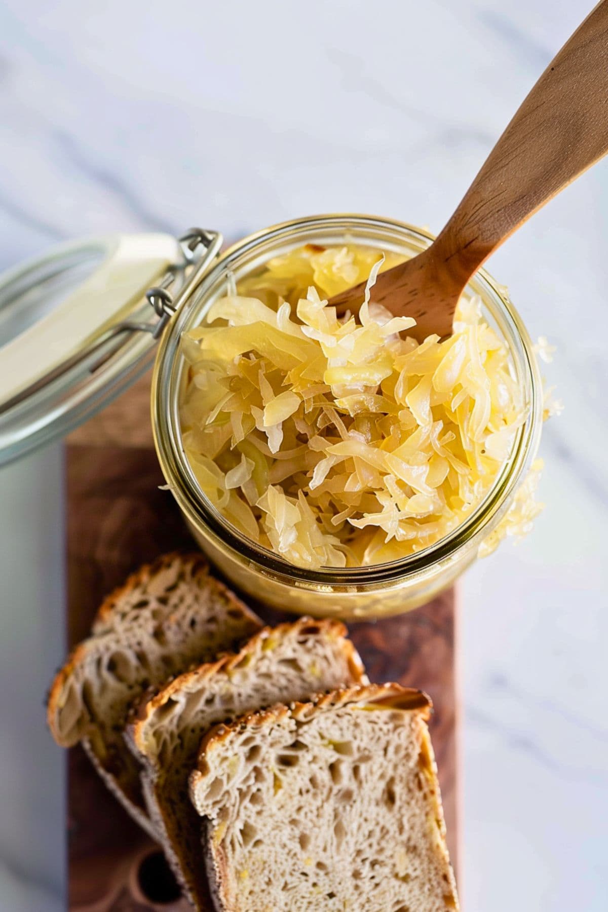 Sauerkraut in a glass jar with slices of rye bread next to it.