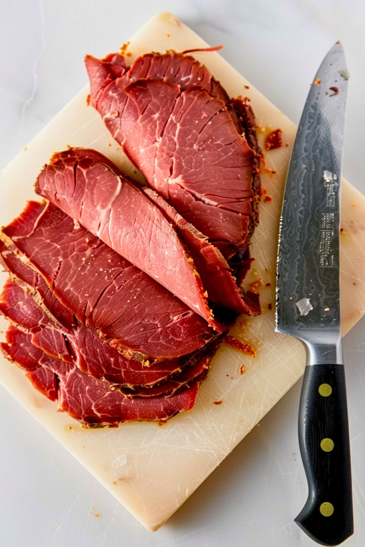 Slices of pastrami on a wooden board.