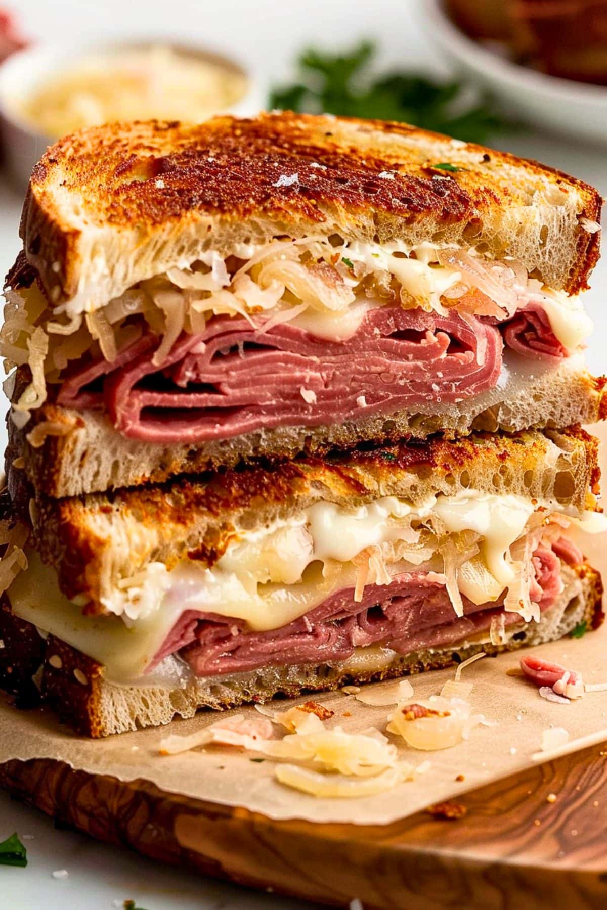 Sliced in half sandwich with thick pastrami slices and sauerkraut and melted cheese filling.