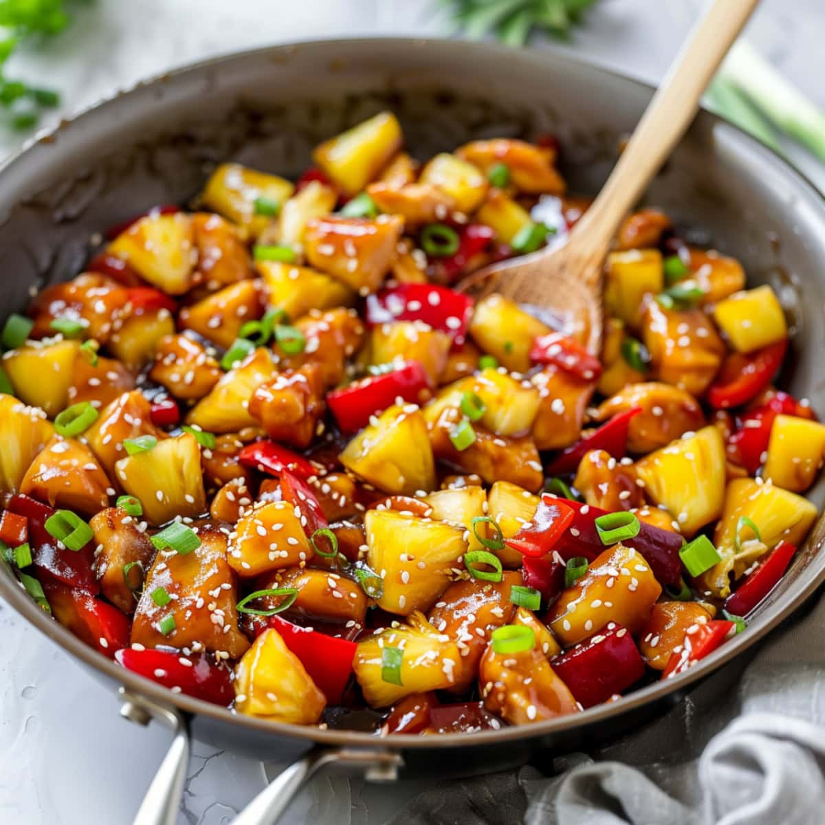 Chicken tenders stir fried in a pan with pineapple chucks and bell peppers.