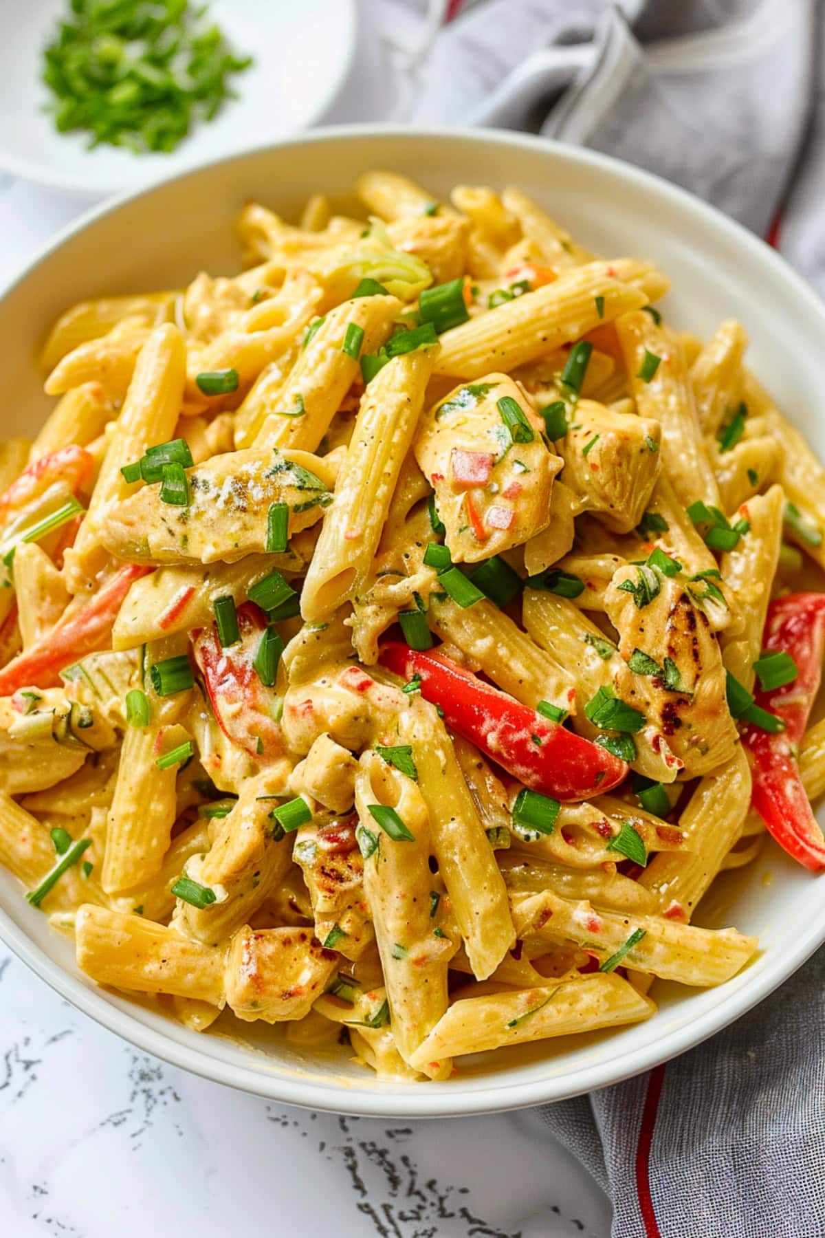 Penne pasta with cream sauce and sweet peppers in a bowl.