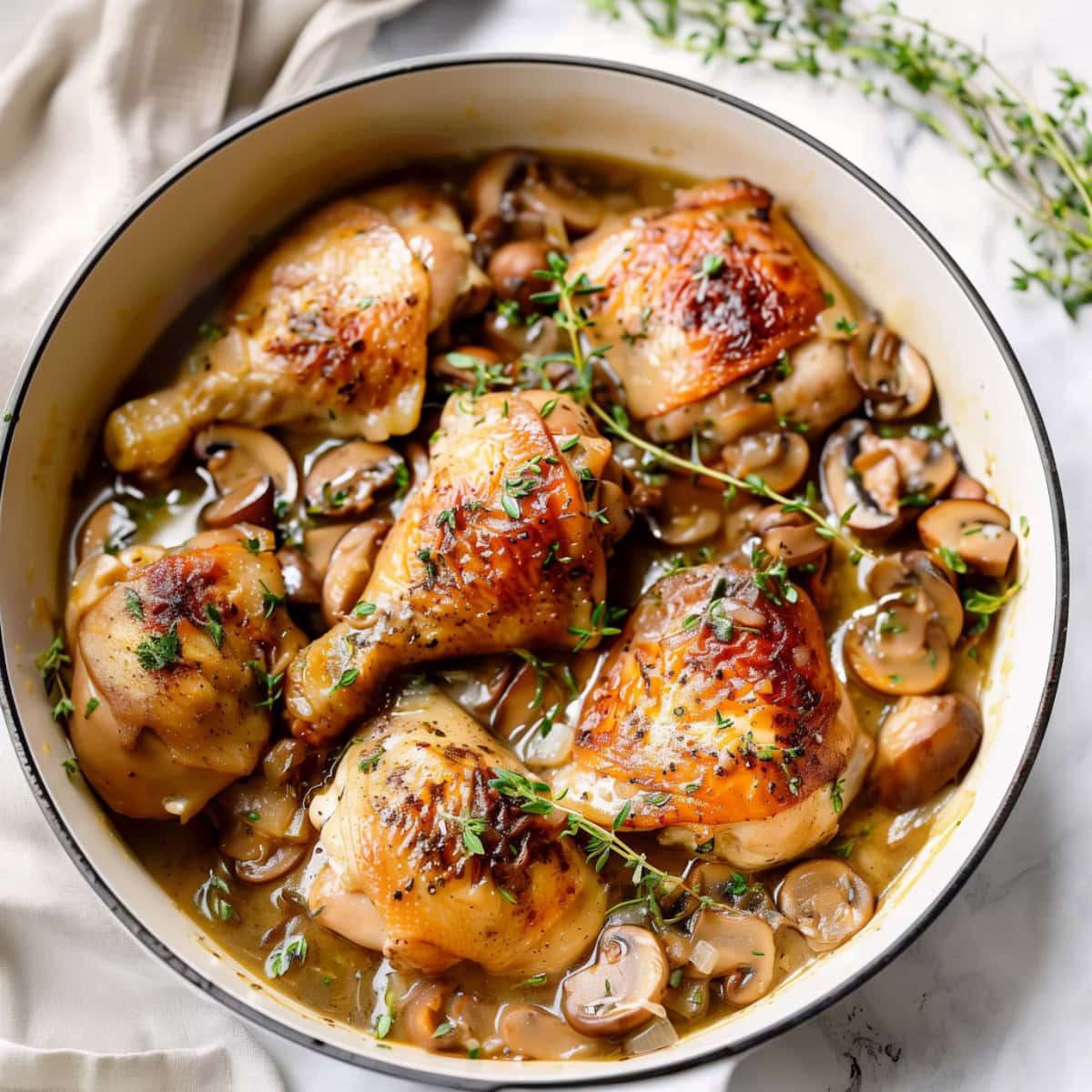 Dutch oven with chicken fricassee, mushrooms, fresh herbs, top view