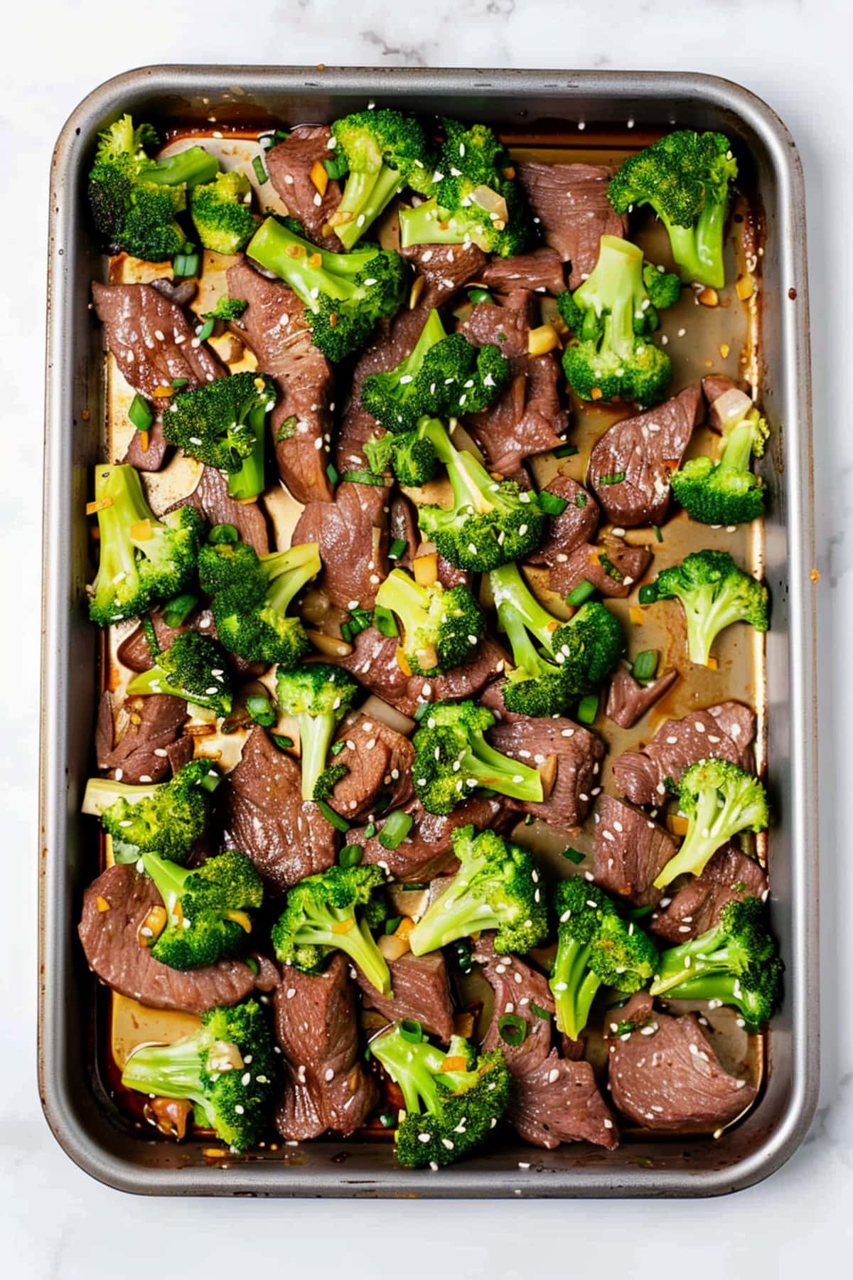 Hearty sheet pan beef and broccoli with sesame seeds and green onions.