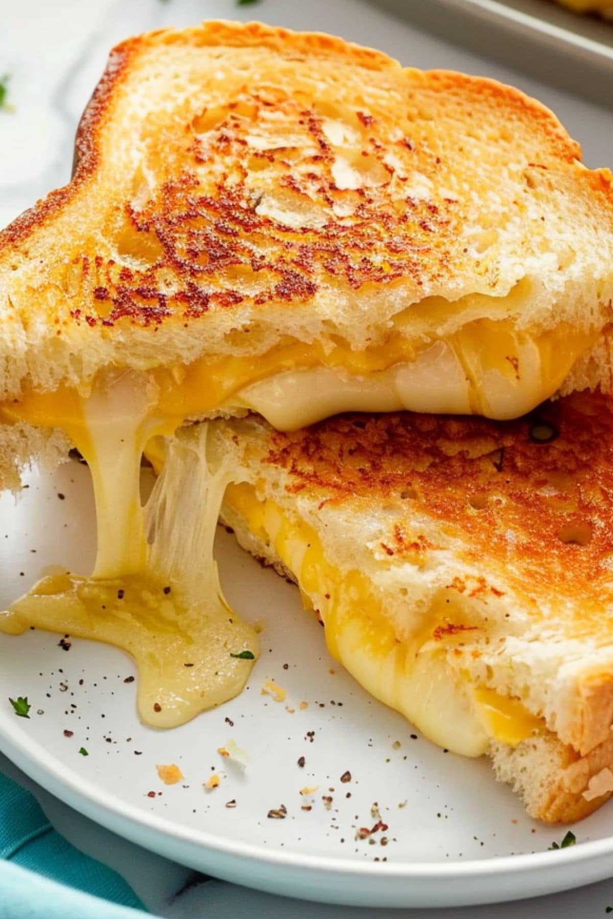 Sliced in half grilled cheese sandwich dripping with cheese filling.