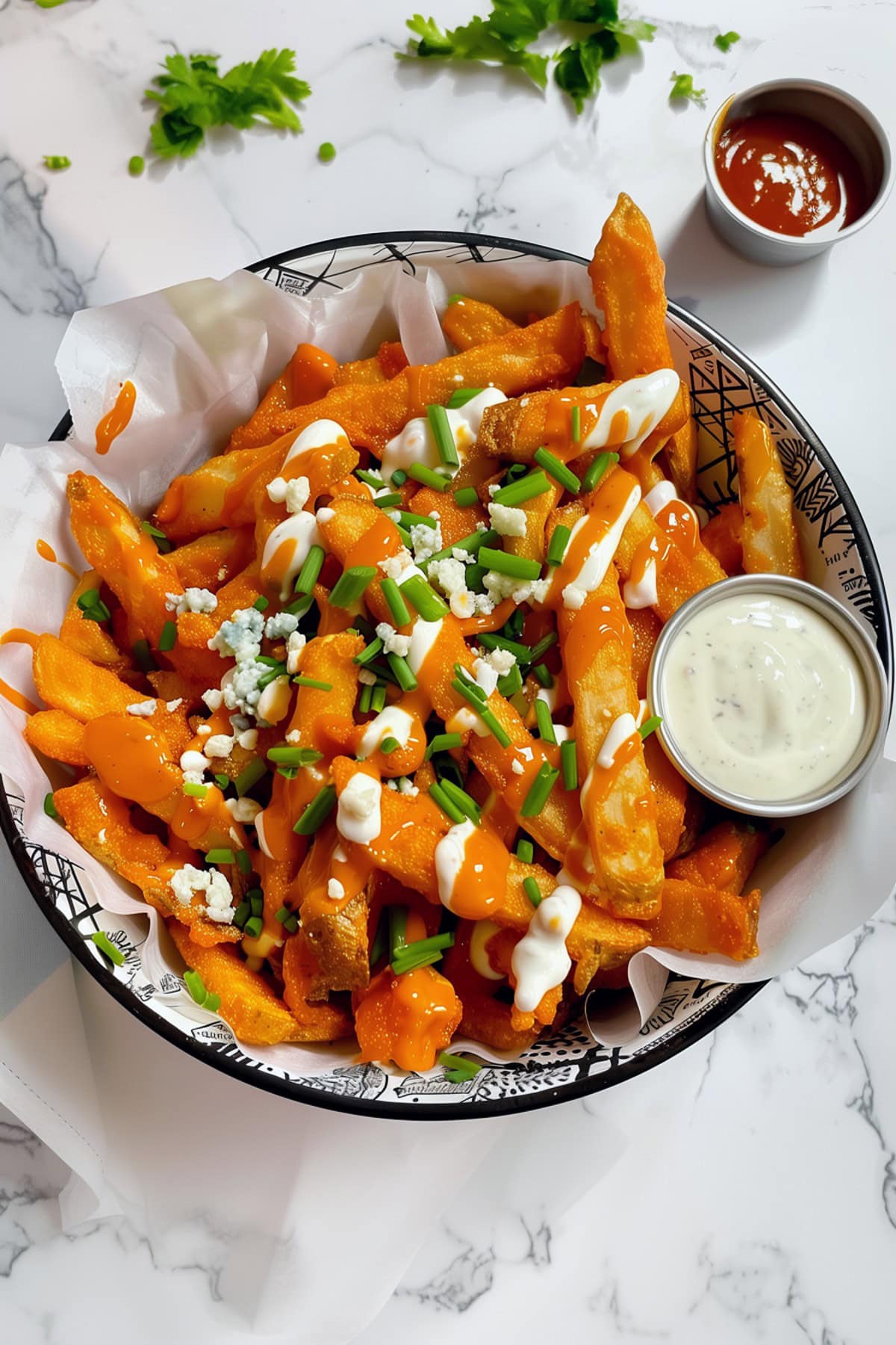 Spicy buffalo fries topped with crumbled blue cheese and chopped chives, served with ranch dressing and ketchup, top down view