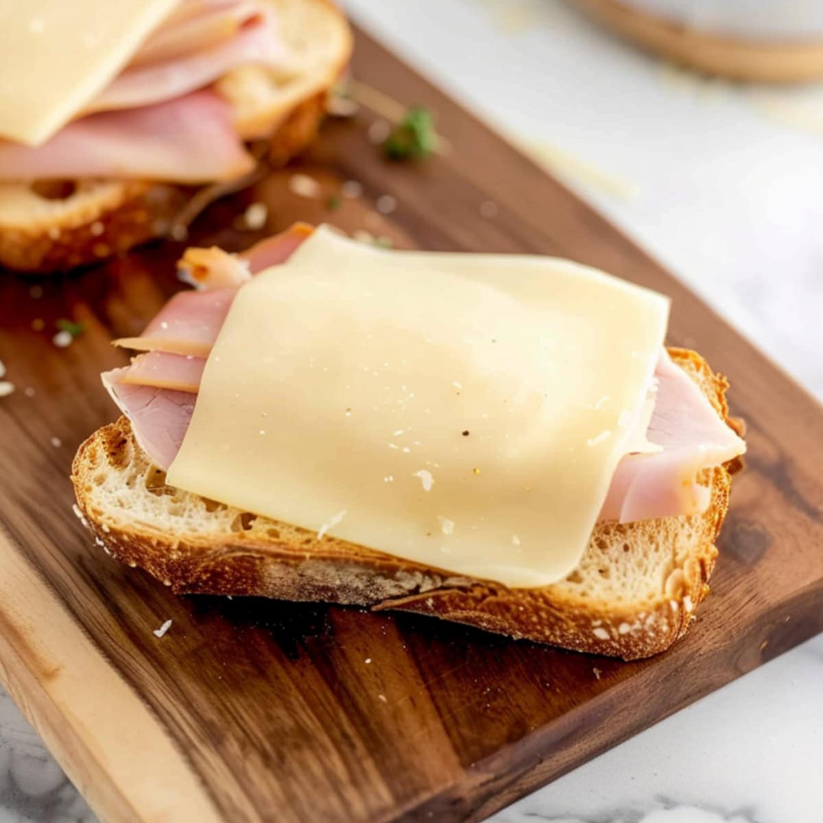 Panini bread with a slice of cheese and ham on top.