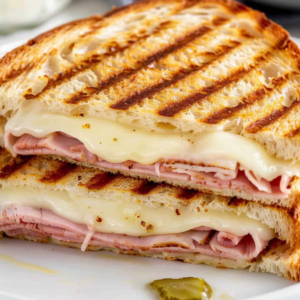 Sliced panini bread sandwich with gooey cheese and ham filling.