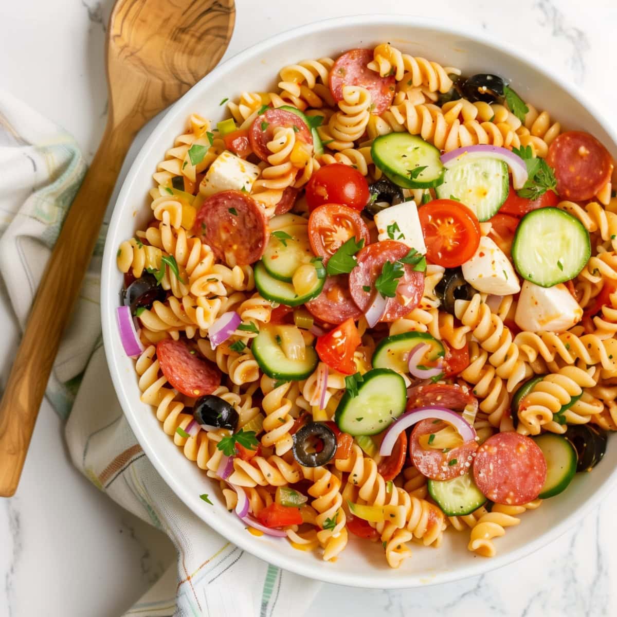 Colorful supreme pasta salad with cherry tomatoes, olives and cucumbers.