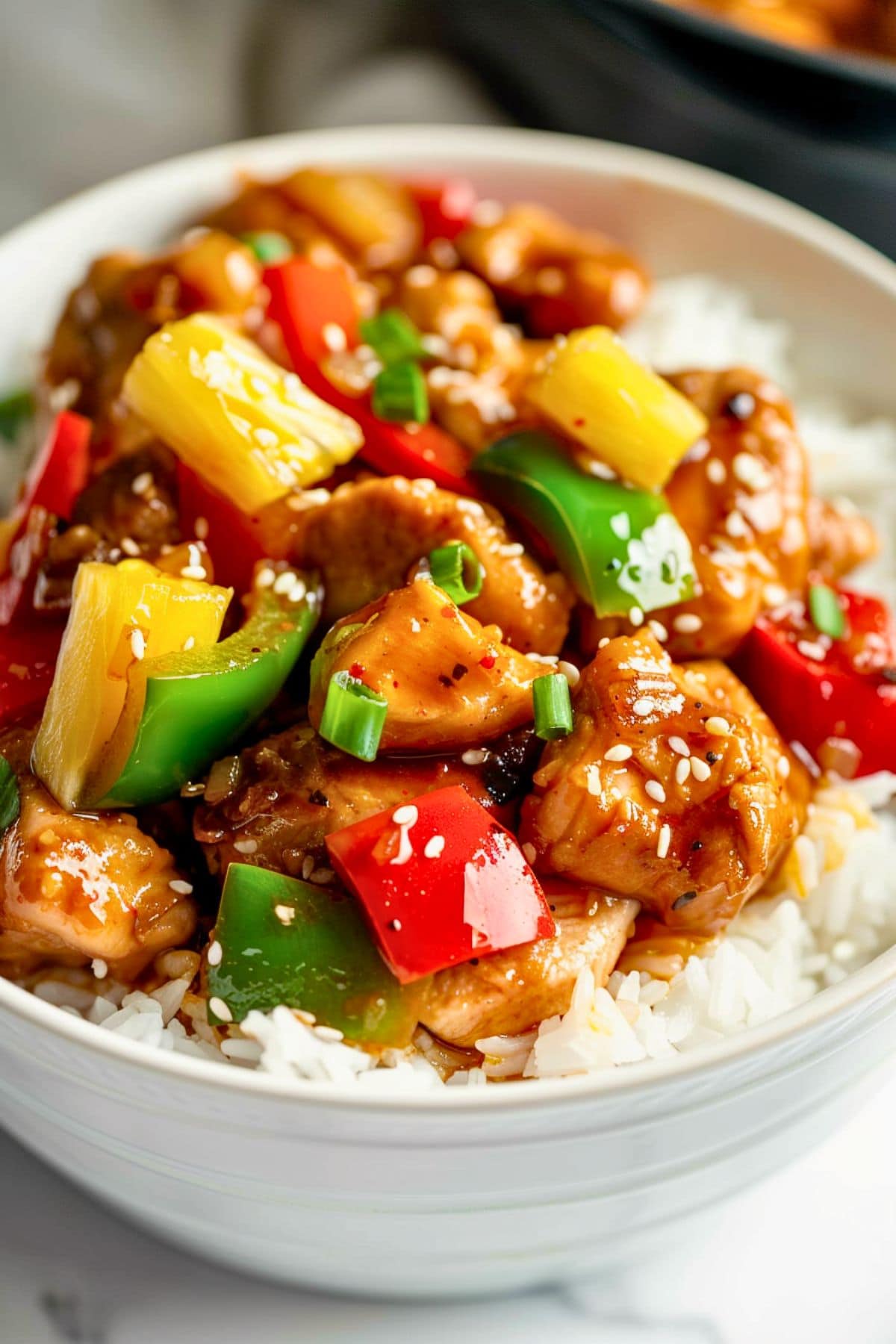 Hawaiian crockpot chicken topped in a white rice on a white bowl.