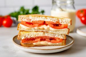 A plate of tomato sandwiches with creamy aioli sauce.