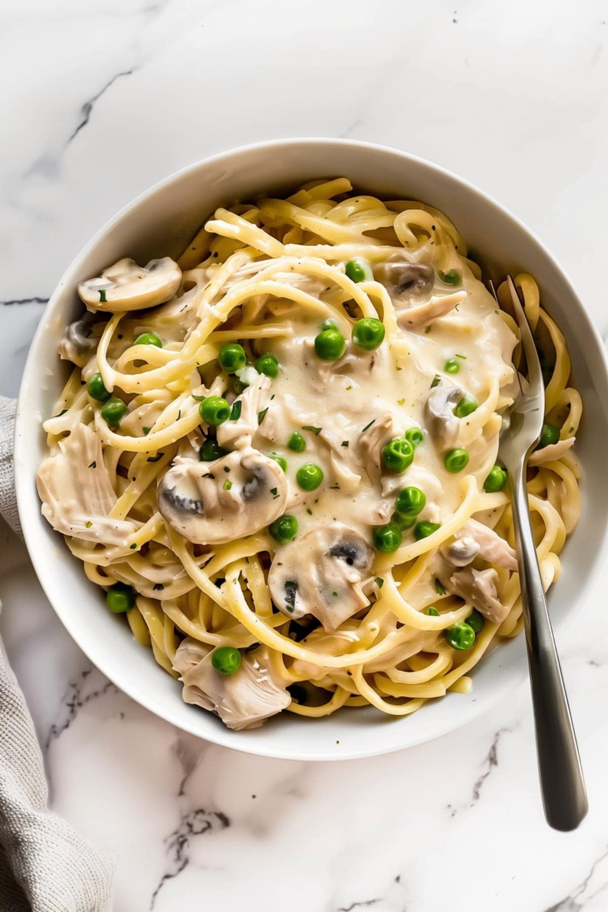 A bowl of turkey tetrazzini with mushrooms and green peas, top down view